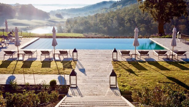 Un espace aménag é au bord de la piscine, avec des chaises longues et des parasols, offrant une vue dégagée sur la piscine, ainsi qu'un chemin menant à la piscine.