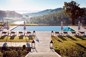 A poolside area with lounge chairs and umbrellas, a clear view of the pool, and a pathway leading to the pool.