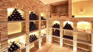 Une cave à vin avec de nombreuses étagères remplies de bouteilles, des murs en briques et un meuble en bois.