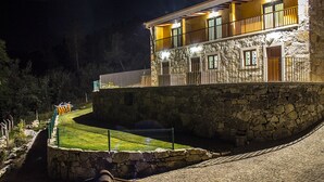 A stone building with a balcony, a stone wall, and a paved area. - Casa Moinho da Mouta (Sabrosa)