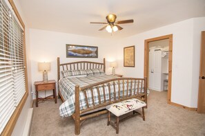 A bedroom with a wooden bed, two bedside tables with lamps, a ceiling fan, and a door leading to a closet.
