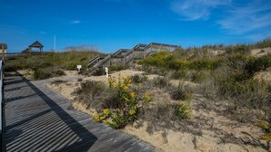 Een houten looppad dat naar een strandgedeelte leidt, met een houten constructie en borden.
