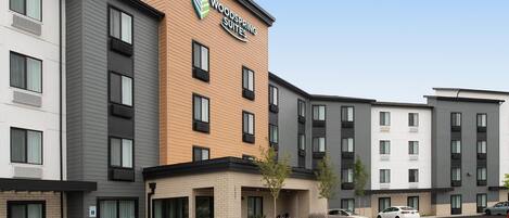 Un hôtel à plusieurs étages, reconnaissable à son enseigne bien visible indiquant « Woodspring Suites ».