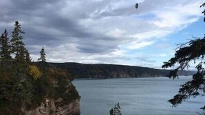A coastal landscape with a rocky cliff, a small island, and a body of water under a cloudy sky. - St. Martins Sea Caves · Oceanfront Retreat (Saint Martins Parish)