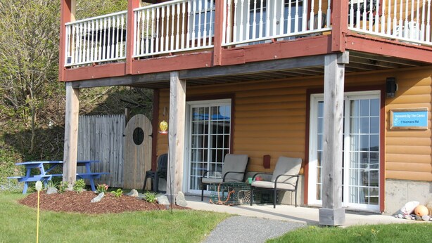 A wooden building with a balcony, outdoor seating, and a sign indicating a restaurant. - St. Martins Sea Caves · Oceanfront Retreat (Saint Martins Parish)