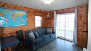 A room with a wooden interior, a large world map on the wall, a sofa, a chair, and a table. - St. Martins Sea Caves · Oceanfront Retreat (Saint Martins Parish)
