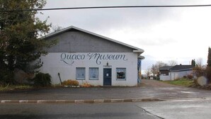 A building labeled 'Quaco Museum' with a simple facade, a small entrance, and a clear sky. - St. Martins Sea Caves · Oceanfront Retreat (Saint Martins Parish)