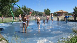 Un parque acuático con una superficie azul, un tobogán de agua verde y un pabellón al fondo.