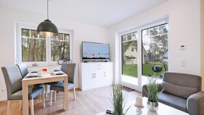 A modern living room with a dining area, large windows, and a view of the outdoors.