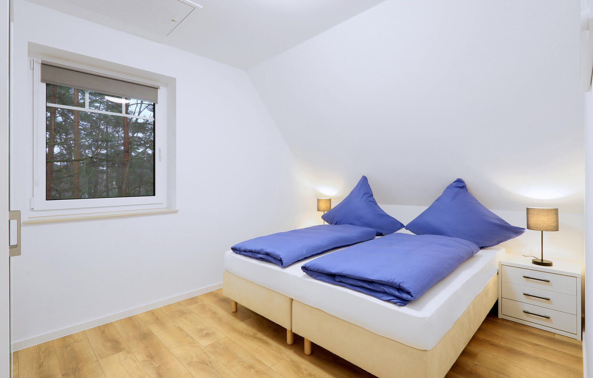 Une chambre à coucher avec un lit, deux lampes de chevet, une fenêtre et une table de chevet.