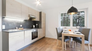 A modern kitchen with wooden cabinets, a built-in oven, and a dining area with a table and chairs.