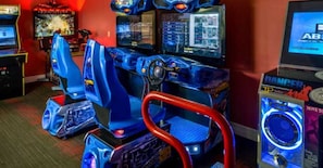 Une rangée de jeux d’arcade de course, avec des sièges bleus et des guidons rouges.