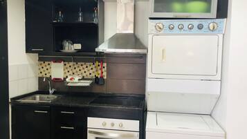 A compact kitchen with a stove, oven, microwave, and a sink.