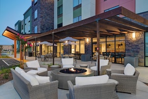 Un patio exterior con mobiliario de mimbre, una chimenea y una zona de estar cubierta con sombrillas.