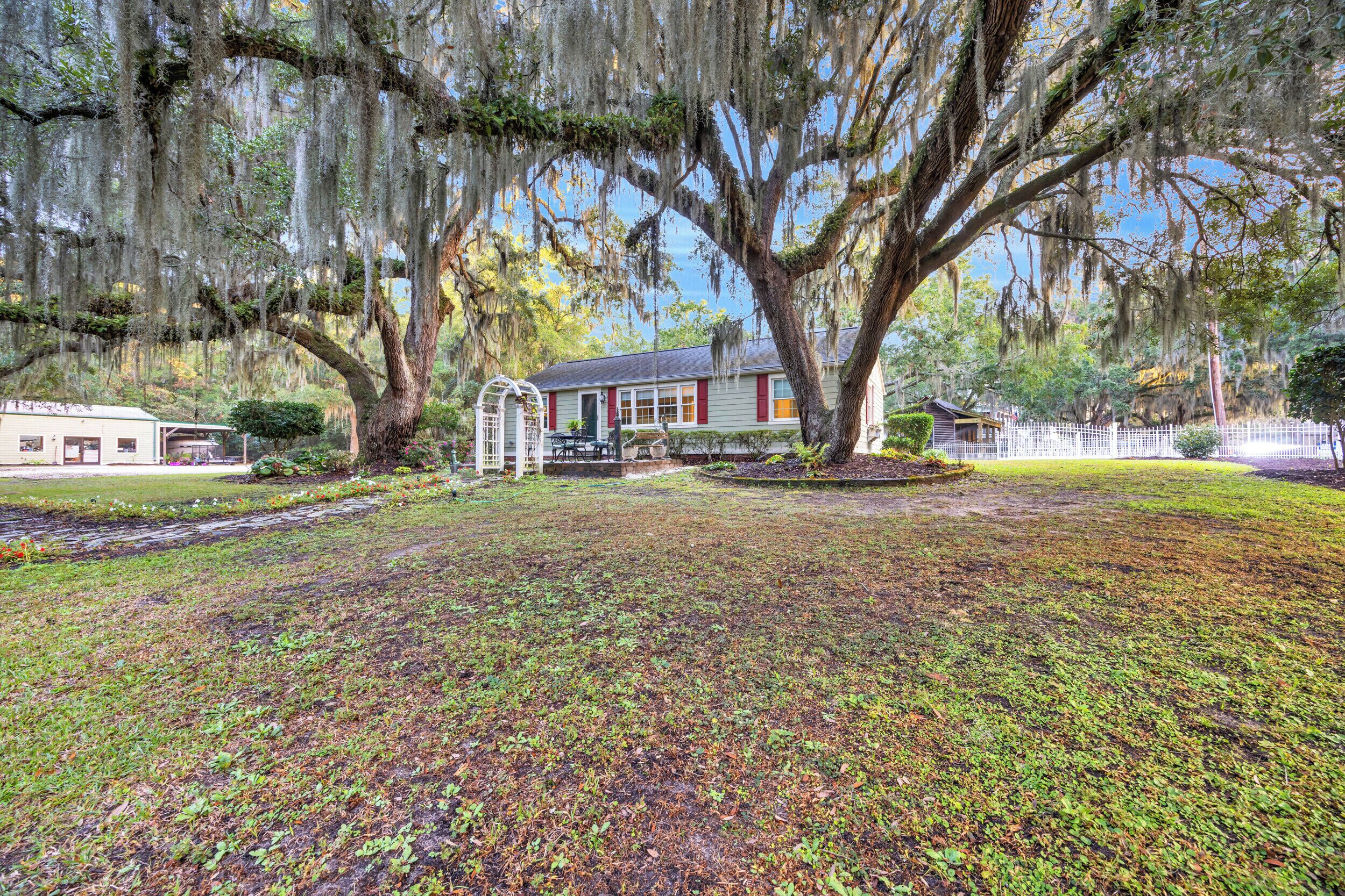A large house with a porch, surrounded by a well-maintained lawn and large trees with Spanish moss.