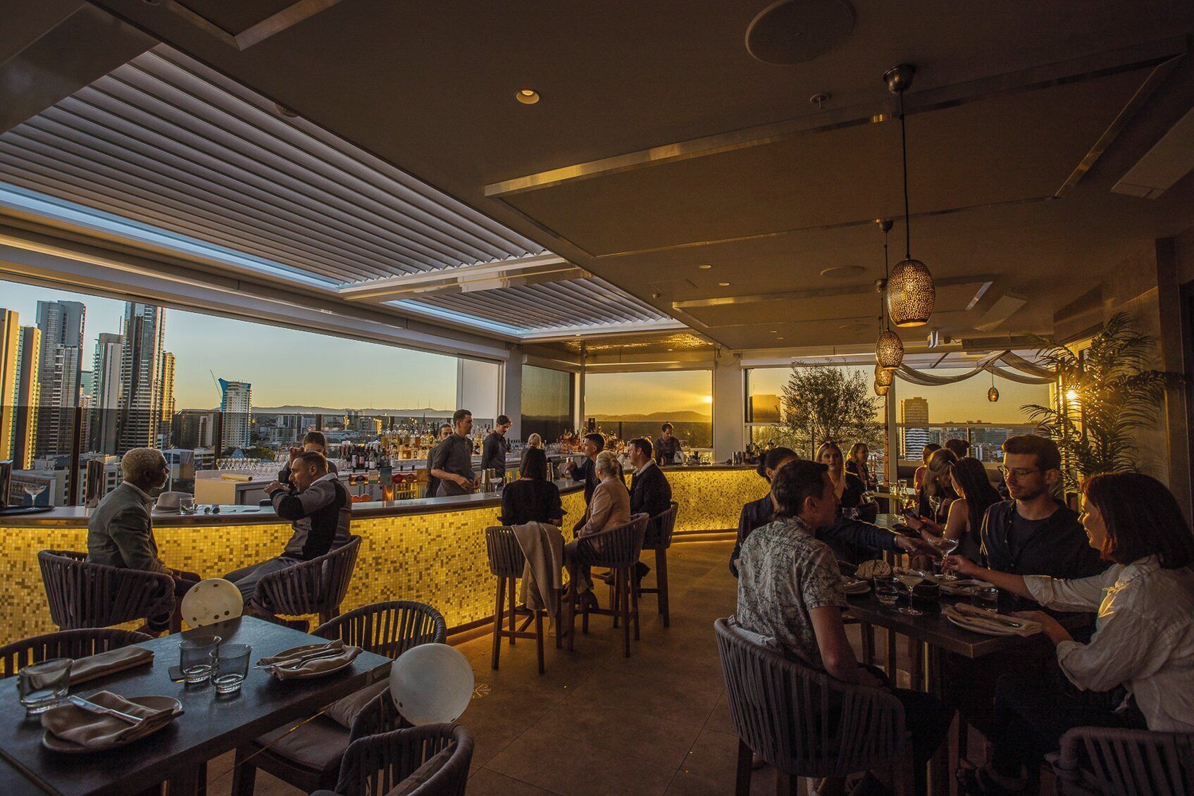A rooftop bar with city views, outdoor seating, and a bar area.
