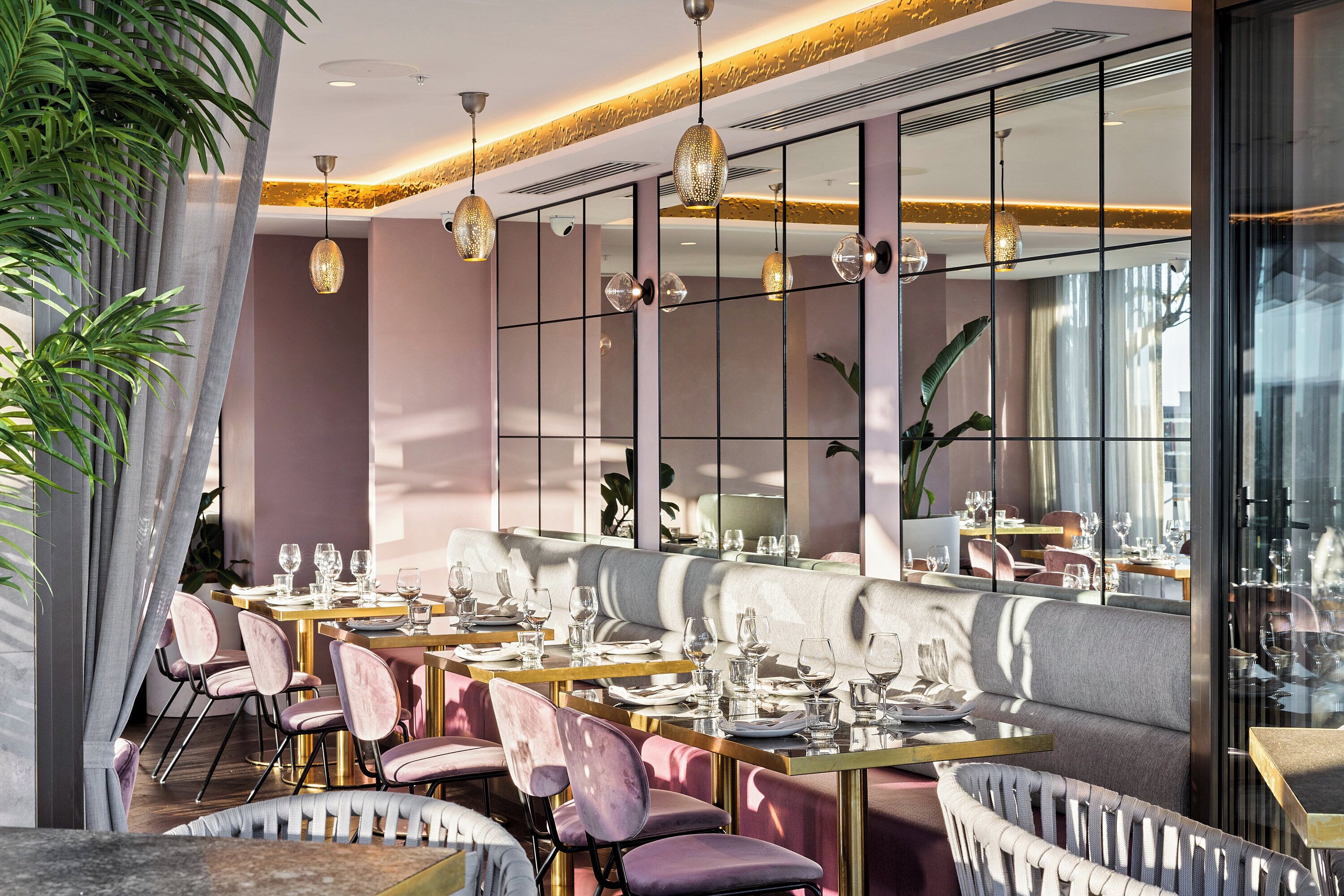 Un restaurante moderno con una larga mesa de comedor, asientos acolchados e iluminación colgante.