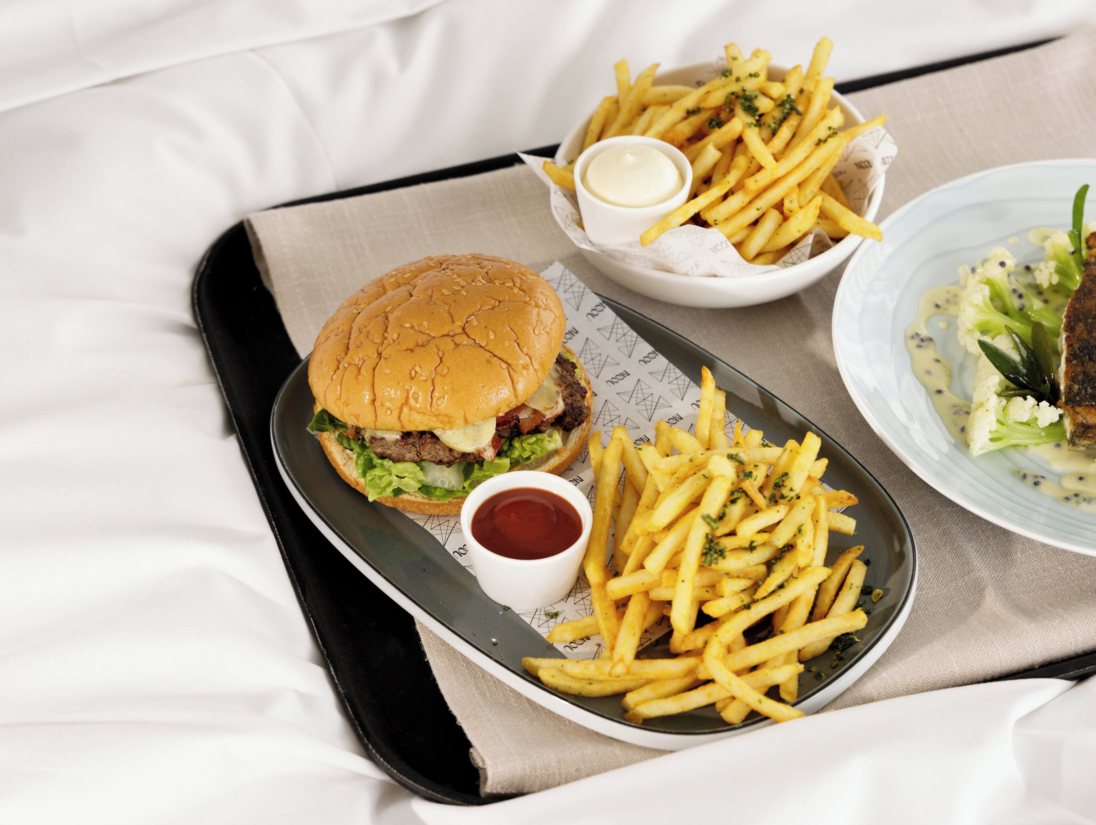 Un plateau avec un hamburger, des frites et une salade d’accompagnement.