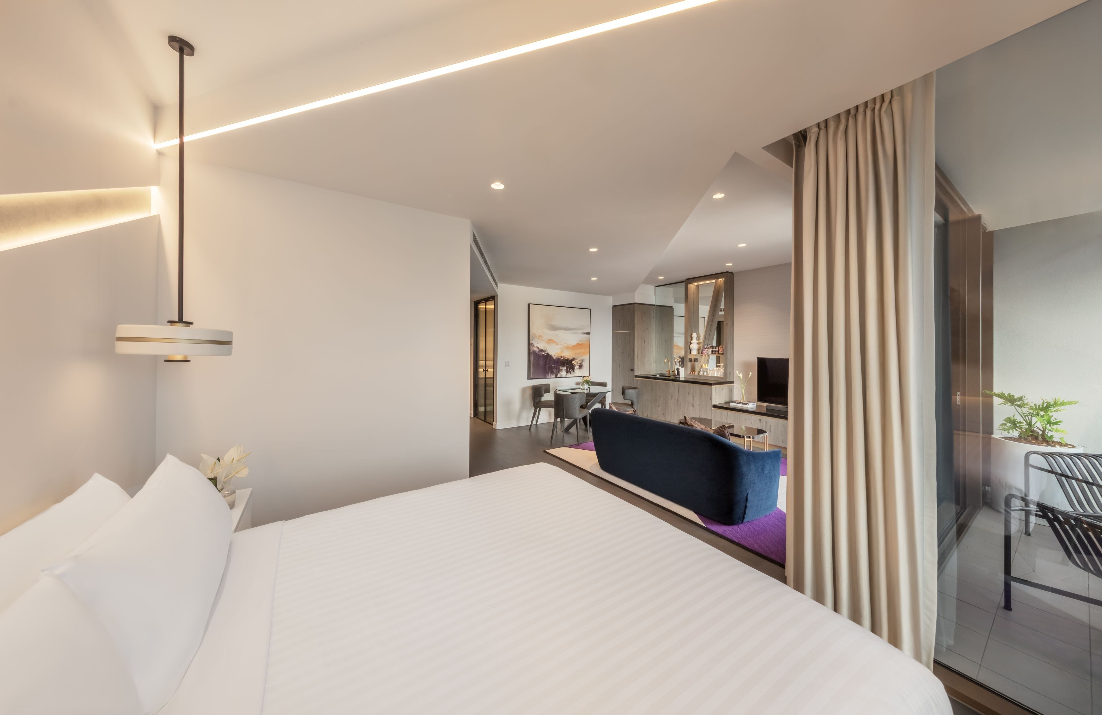 A modern hotel room with a large bed, a desk, and a seating area.