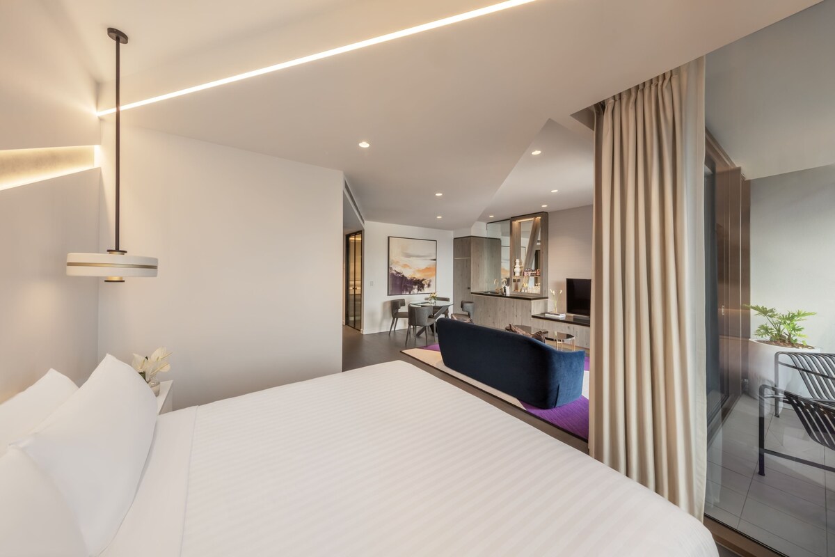 Una habitación de hotel moderna con una cama grande, un escritorio y un espacio para sentarse.