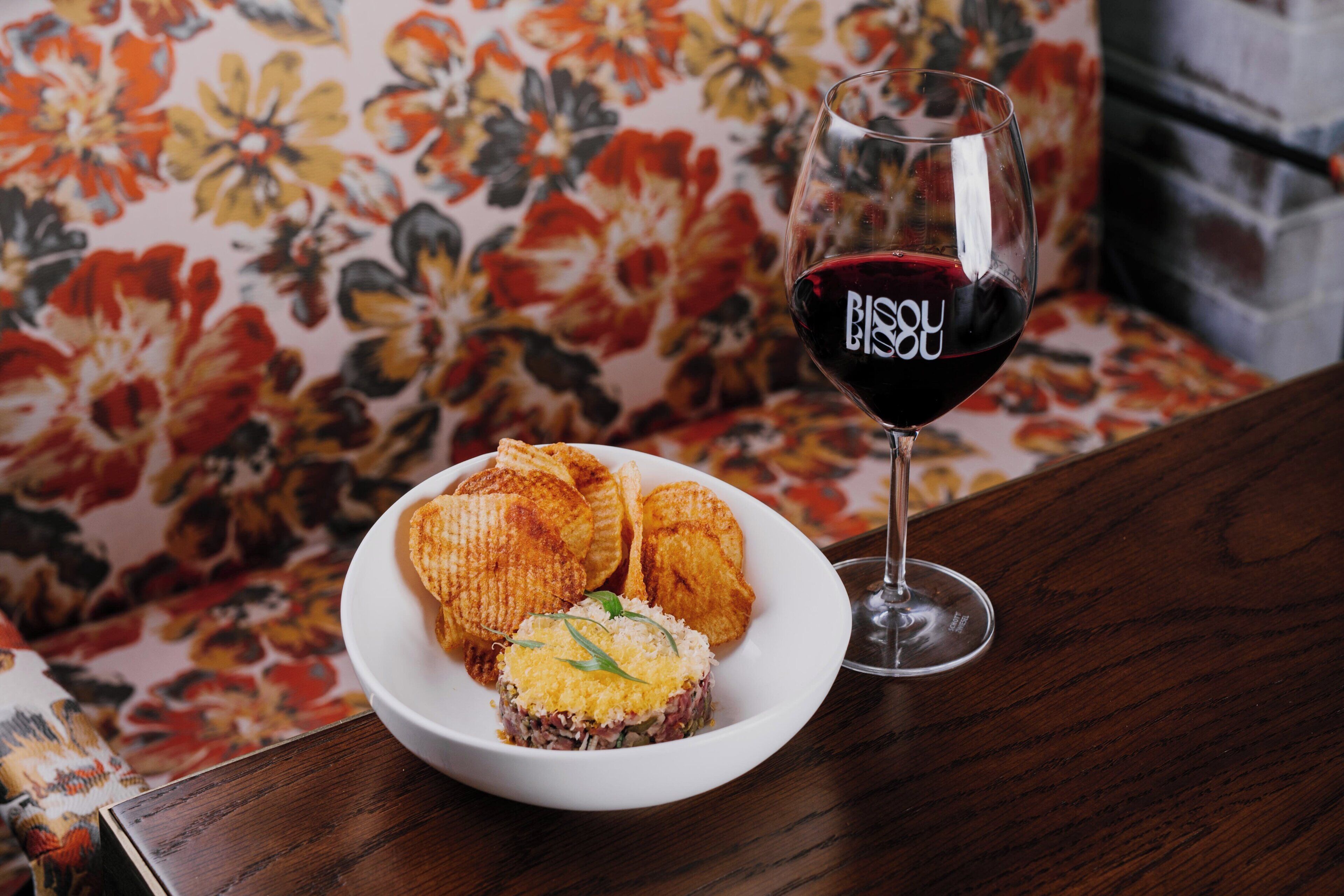 A plate with food and a glass of red wine on a wooden table.