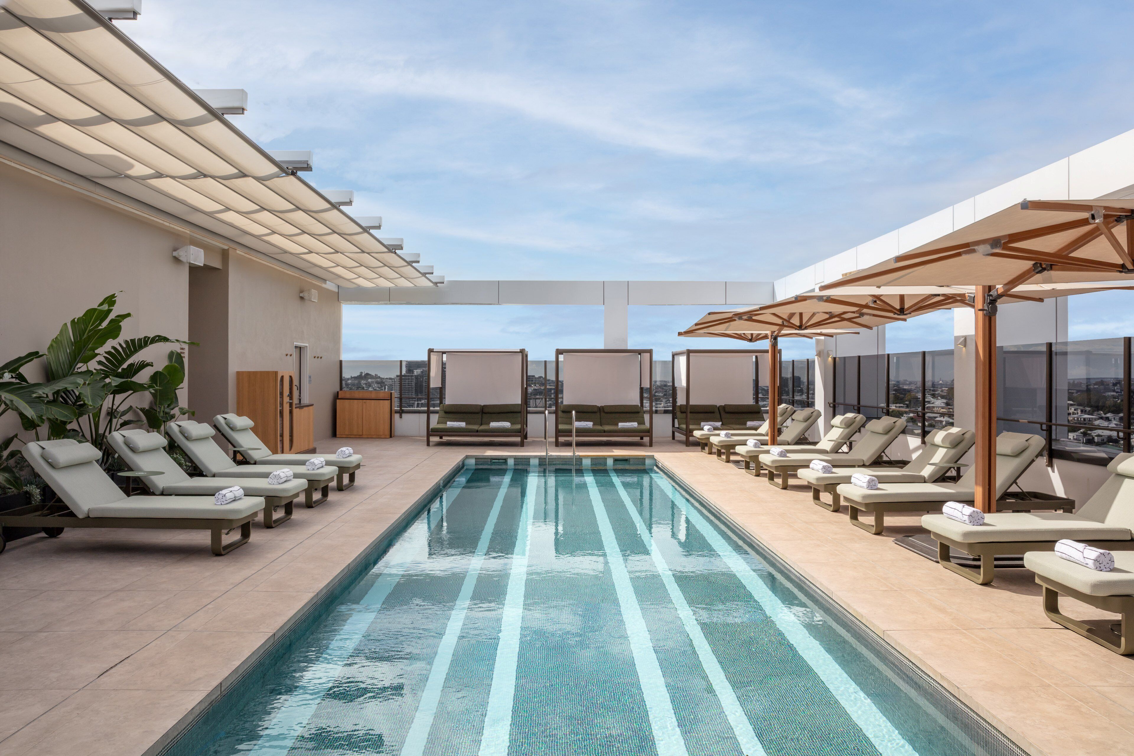 A rooftop pool area with lounge chairs and a view of the city.
