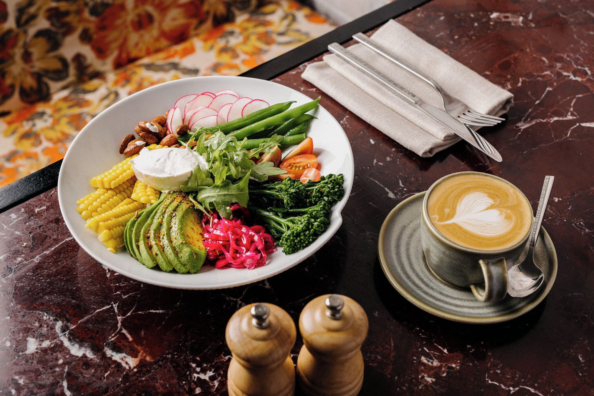 En tallerken med mad, grøntsager og en kop kaffe på et marmorbord.