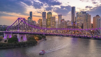 A bridge with purple lights, a river, and a city skyline with tall buildings.
