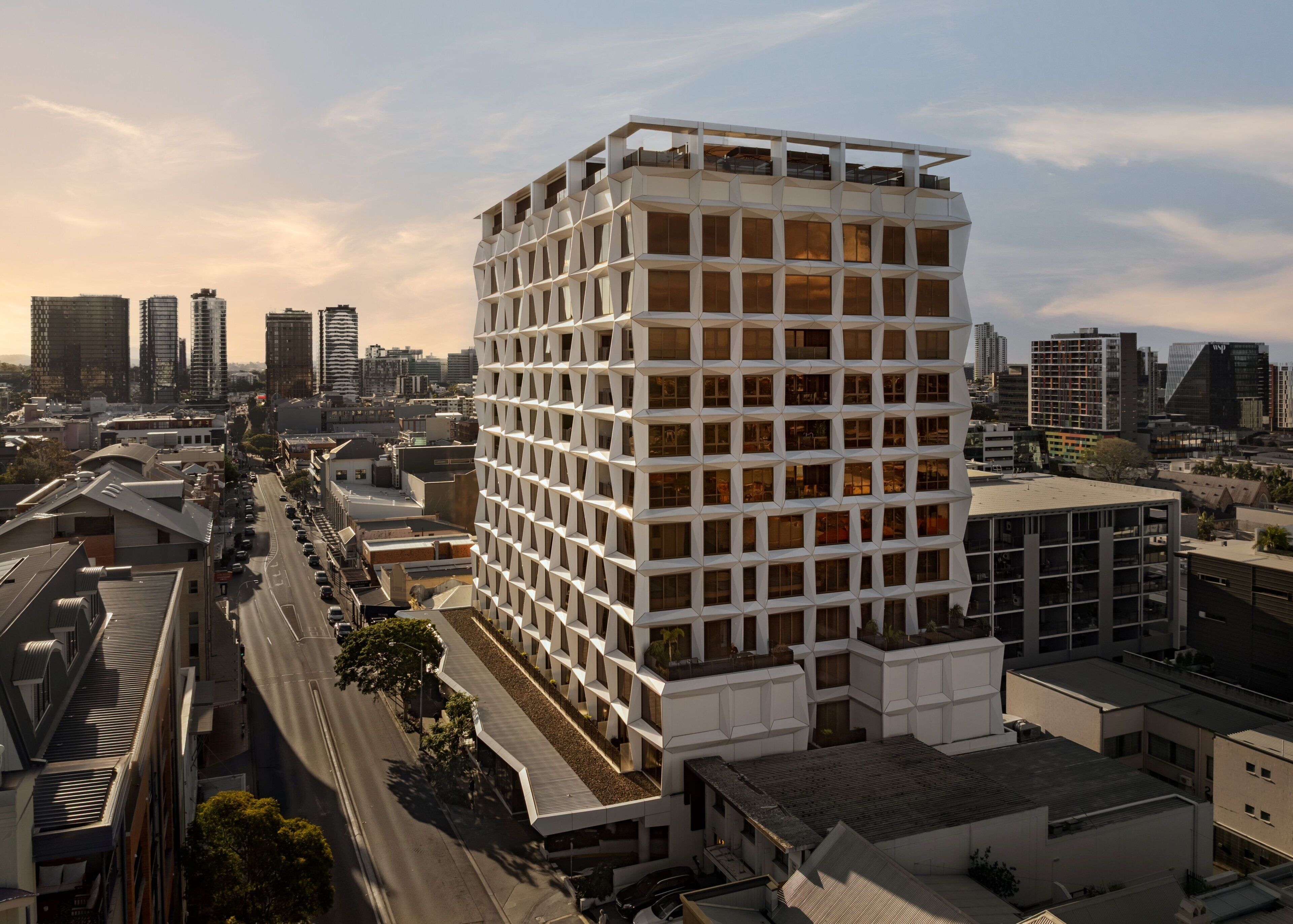 A modern high-rise building with a grid-like facade, surrounded by other buildings and a street.