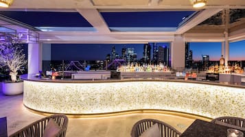 A modern bar with a city skyline view, a tiled backsplash, and seating area.