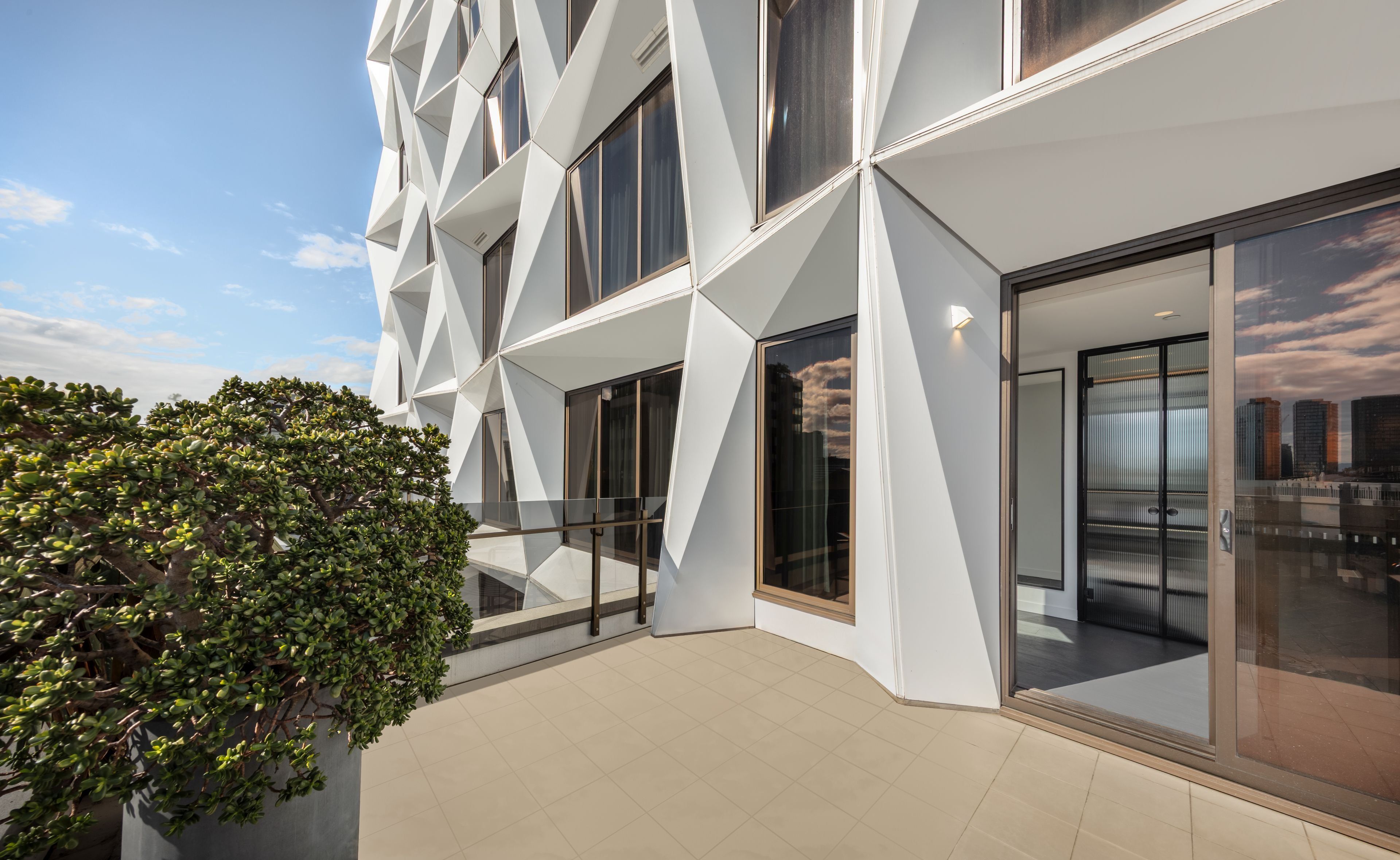 A modern building with geometric facade, large windows, and a balcony area.