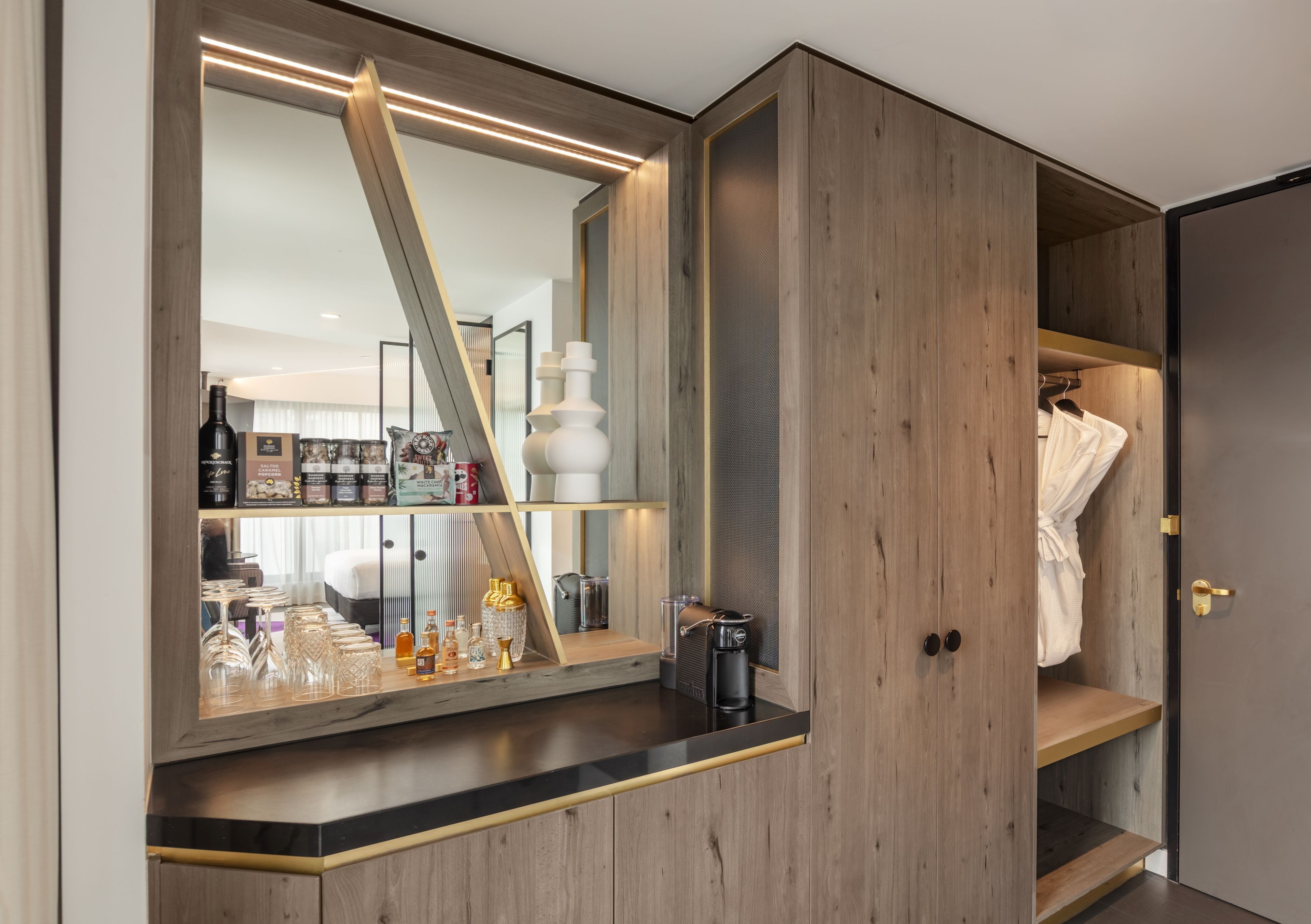A modern bathroom with a large mirror, wooden cabinetry, and a vanity area with toiletries.