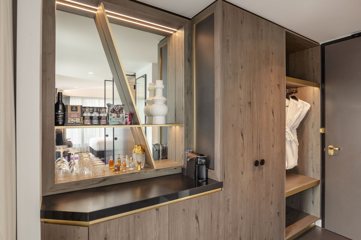 Un baño moderno con un espejo grande, muebles de madera y una zona de tocador con artículos de aseo.