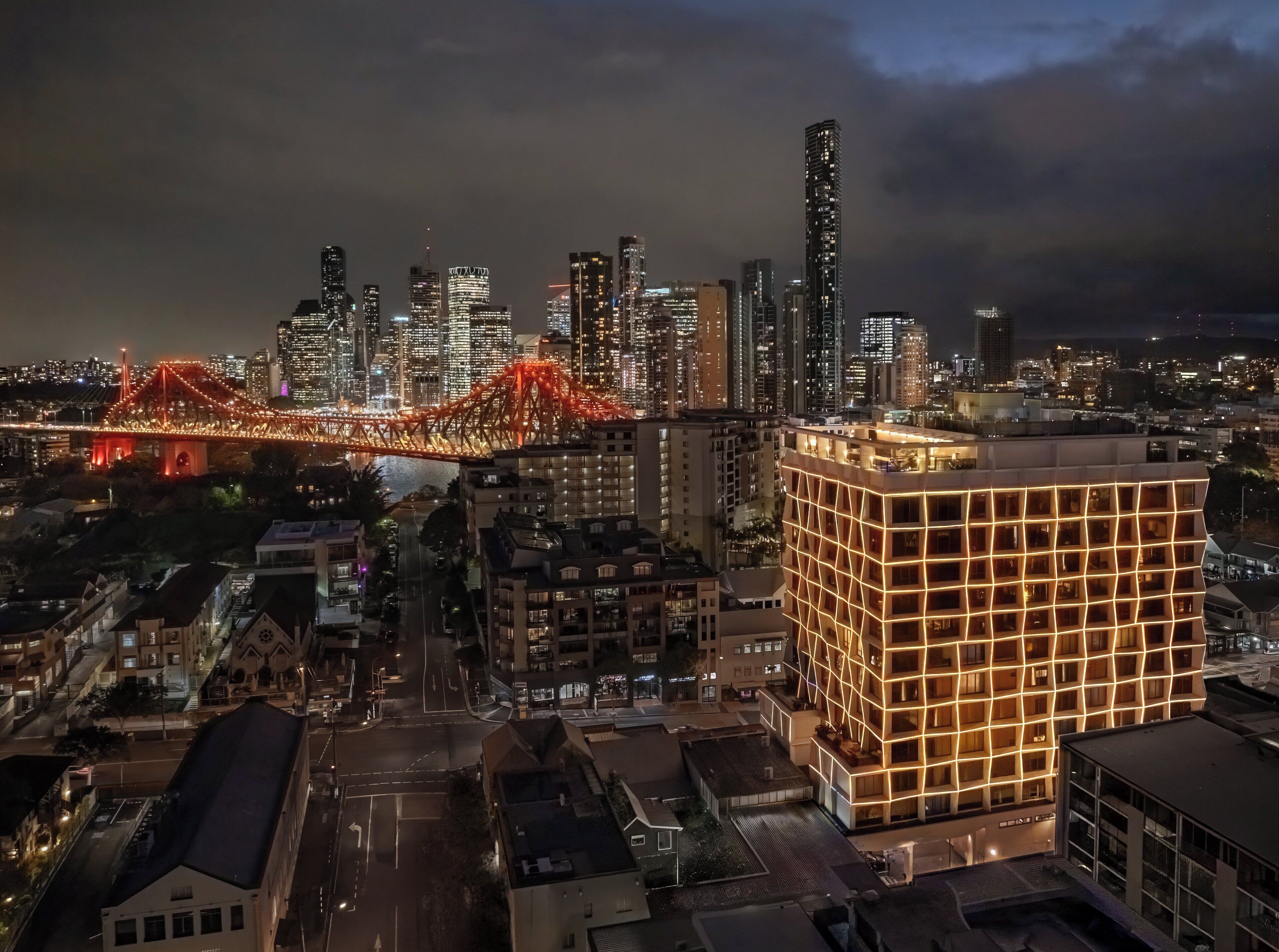 A cityscape at night with illuminated buildings and a bridge.