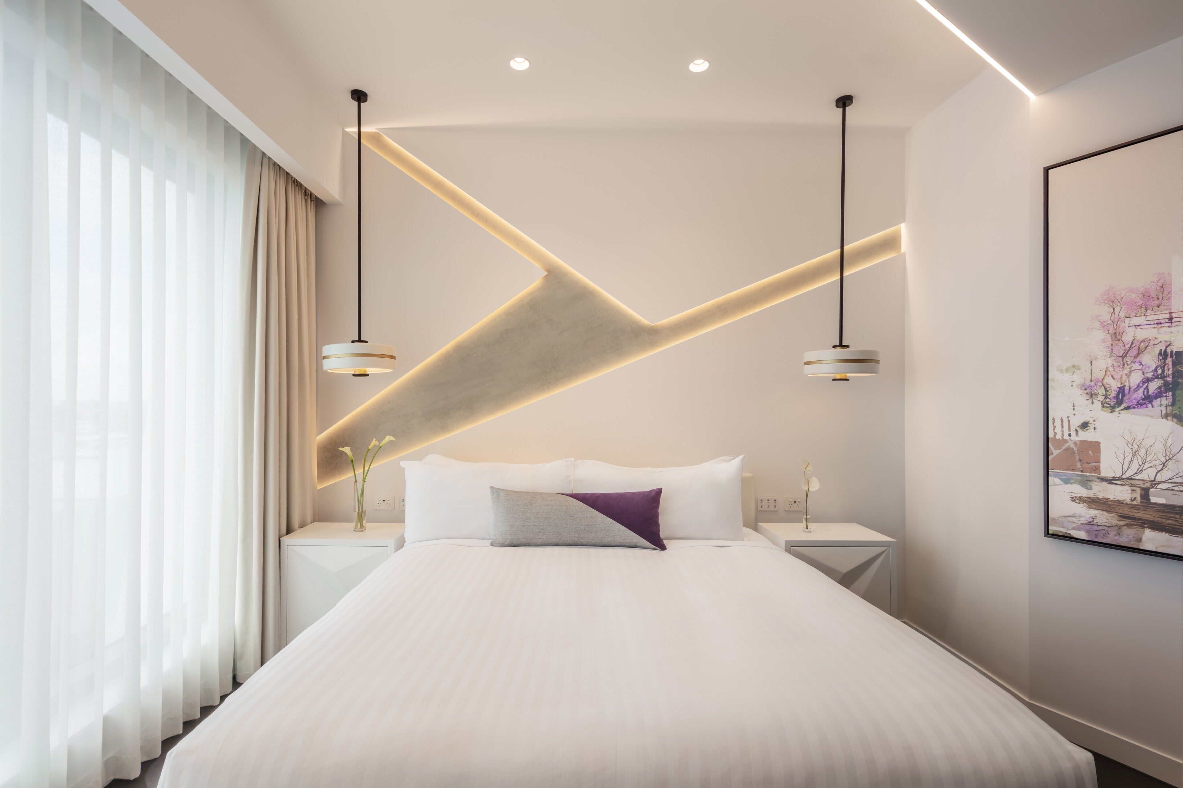 Ein modernes Schlafzimmer mit einem großen Bett, zwei Nachttischen, einer Wandleuchte und einem Gemälde.
