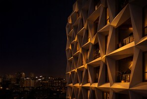 Um edifício moderno com fachada geométrica e várias varandas.