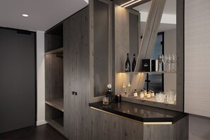Una cocina moderna con armarios de madera, encimera negra y una estantería empotrada para vinos con botellas y copas.