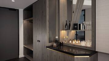 A modern bar area with a wooden finish, a mirrored wall, and a selection of bottles and glasses.