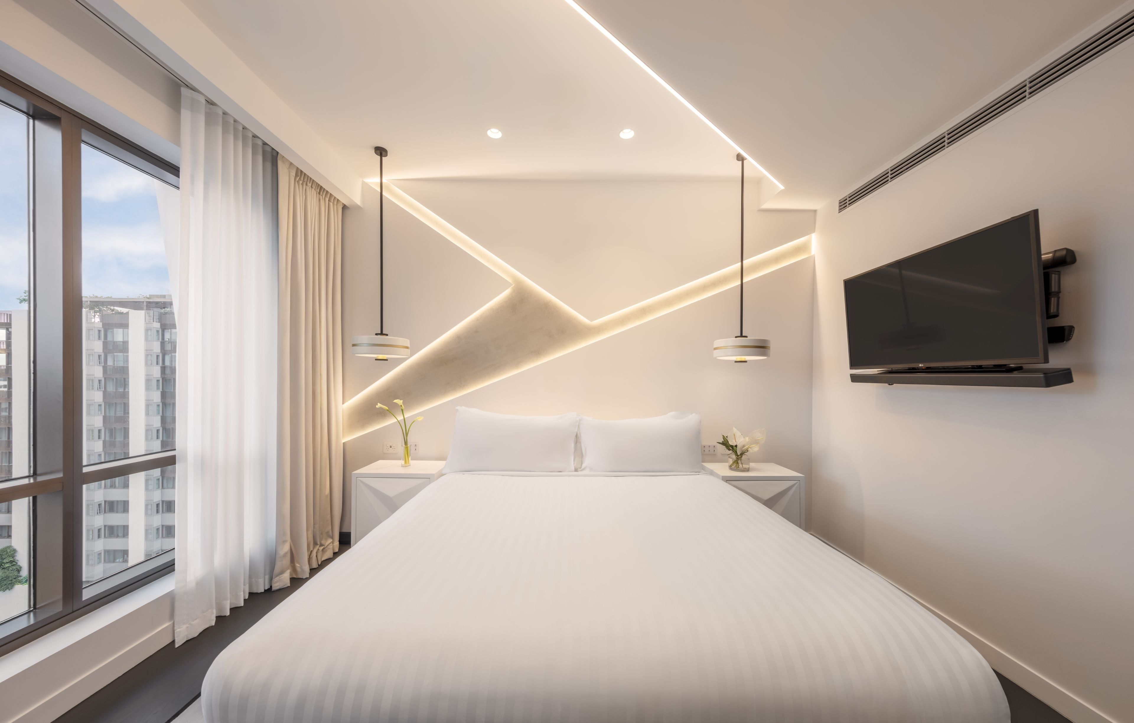 Una habitación de hotel moderna con una cama grande, una televisión de pantalla plana y vistas a la ciudad.