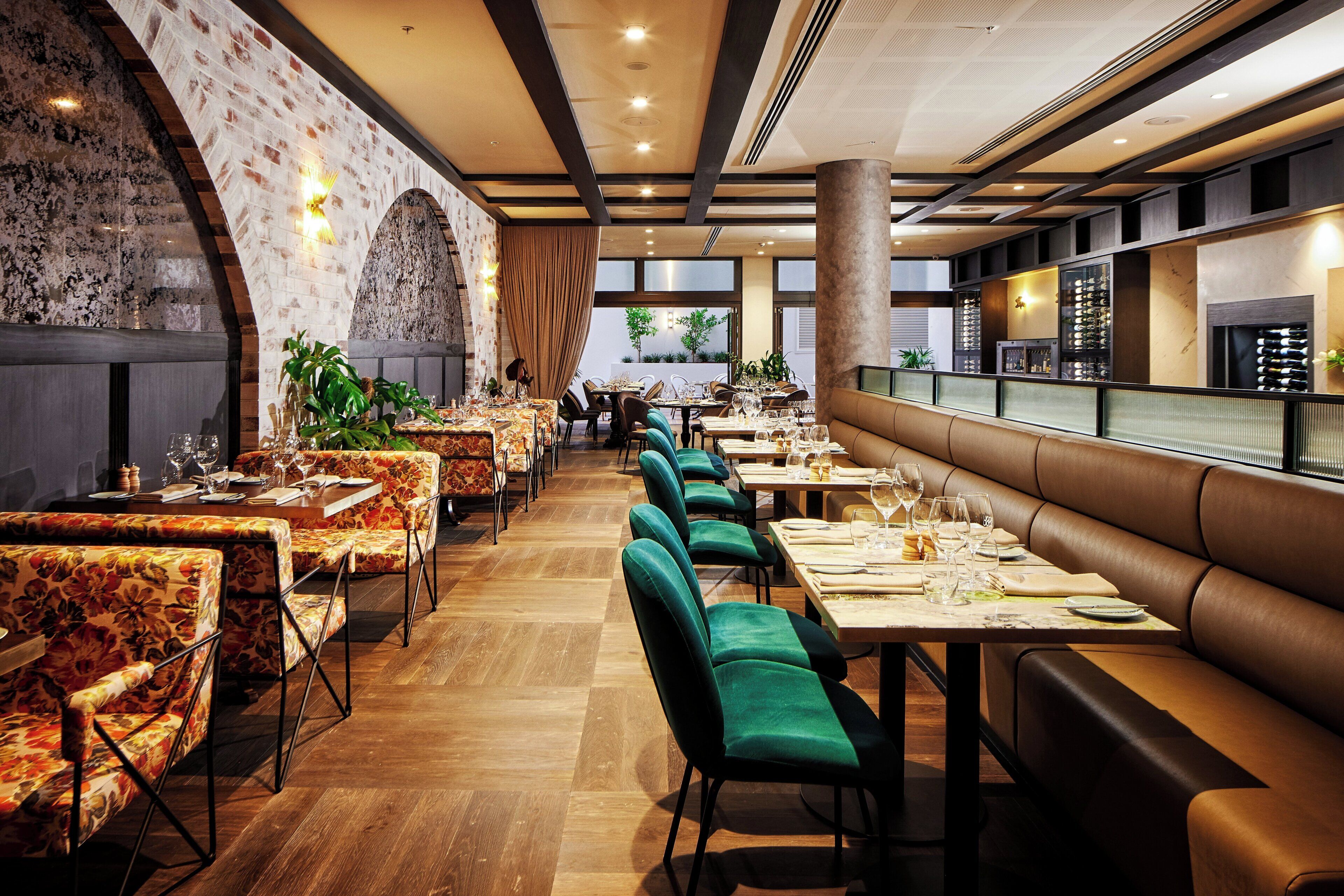 A restaurant with a long counter, booths, and a brick wall.