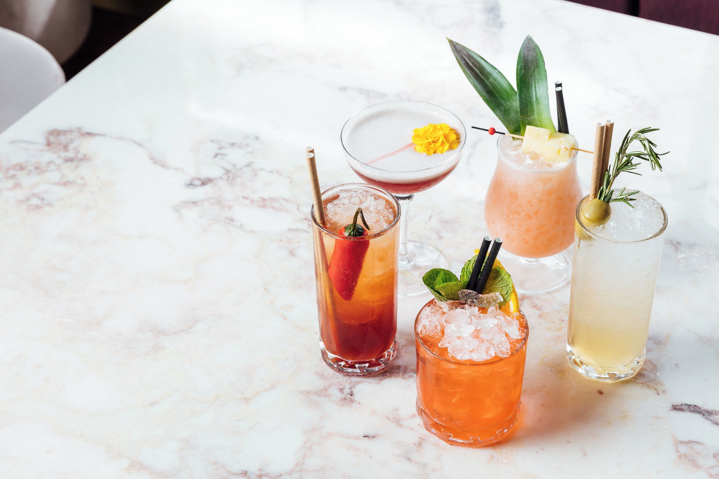 Four cocktails on a marble table.