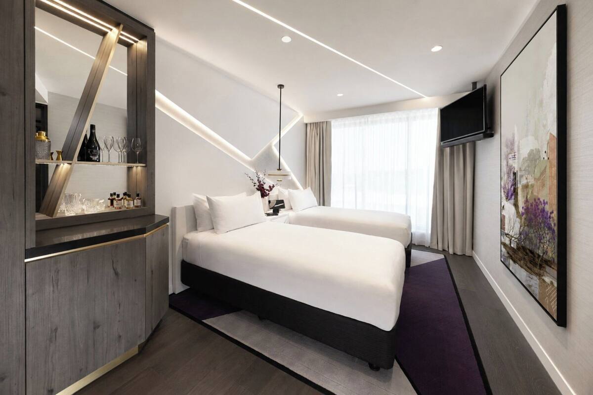 Een moderne hotelkamer met een groot bed, een nachtkastje, een spiegel, een televisie en een schilderij aan de muur.