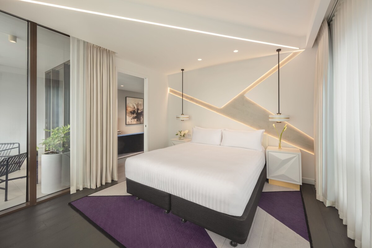 Una habitación de hotel moderna con una cama grande, un escritorio y una silla.