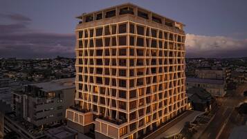 A multi-story hotel with a grid-like facade and illuminated windows at dusk.