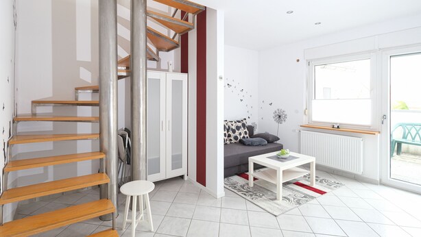 A modern apartment with a spiral staircase, a sofa, a coffee table, and a large window.