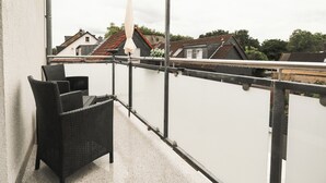 A balcony with wicker furniture and a white umbrella.