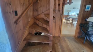 Eine Holztreppe mit Handlauf, die zu einem Essbereich mit Tisch und Stühlen führt.