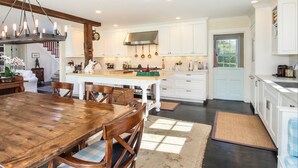 A spacious kitchen with white cabinets, a wooden dining table, and a chandelier. - Chatham Calling... Close to Town & Bocce (Chatham)