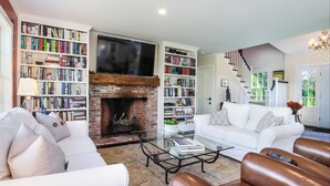 A living room with a fireplace, bookshelves, a white sofa, leather armchairs, and a staircase. - Chatham Calling... Close to Town & Bocce (Chatham)