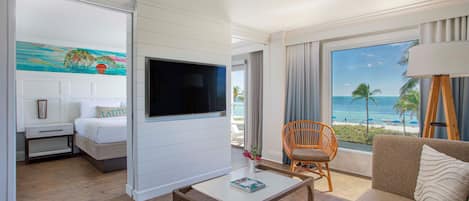 Een hotelkamer met een bed, een televisie, een salontafel, een bank en uitzicht op de oceaan.